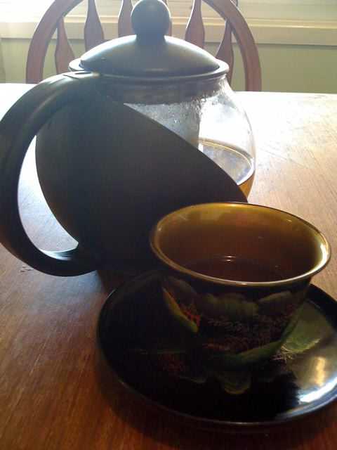 Chinese tea cup and pot with herbal tea.